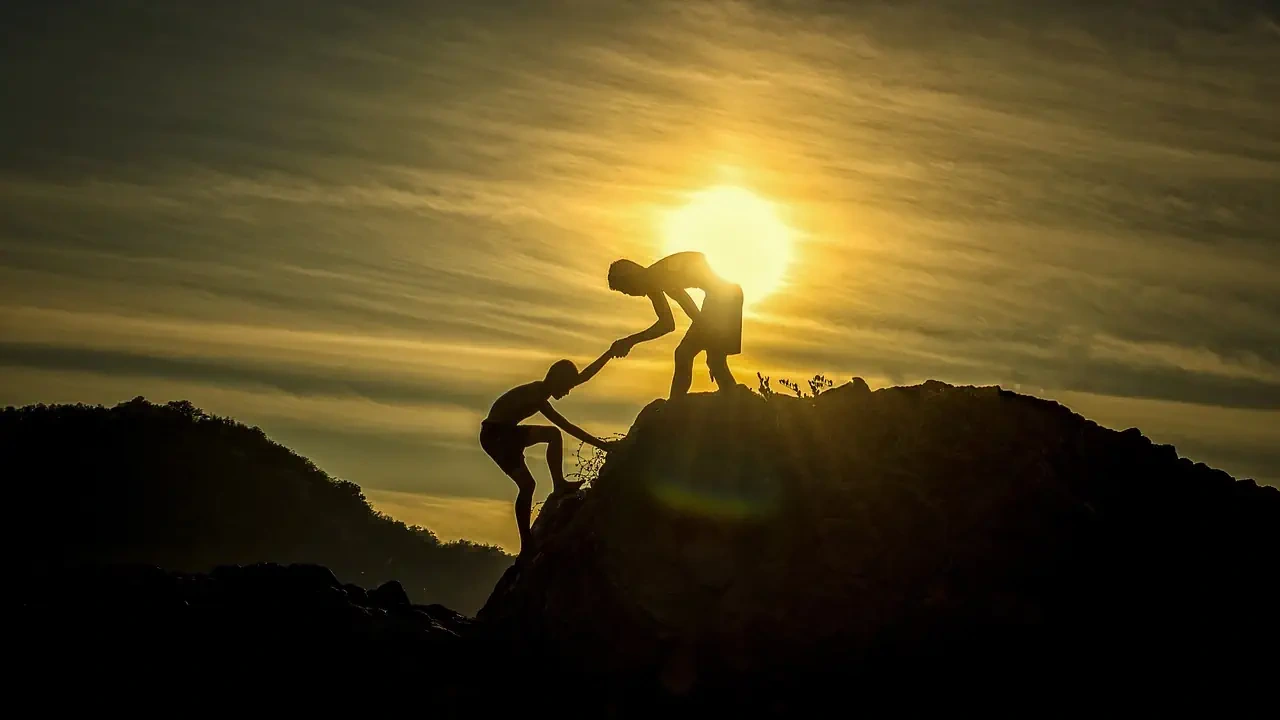 friend helping his other friend climb a mountain